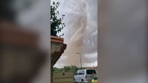 Image of a tornado with a car in the foreground.