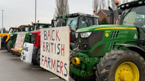 BBC A row of tractors bearing signs, parked up.