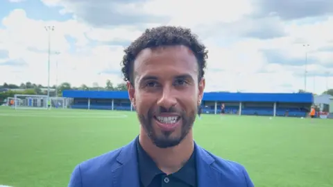 BBC Sam Cox with football ground behind him