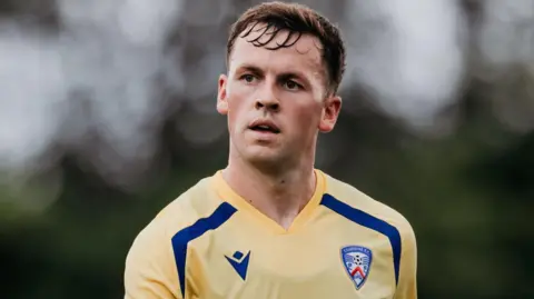 Dylan Kirkpatrick / Copa Foyle de O'Neill. Ben Doherty tiene el pelo corto y castaño y lleva puesta una camiseta de entrenamiento azul y amarilla del Coleraine FC.