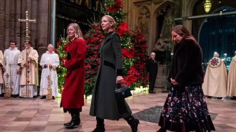 PA Media Lady Helen Taylor, Lady Gabriella Windsor and a third woman walk into Westminster Abbey with a Christmas tree and some priests stood behind them