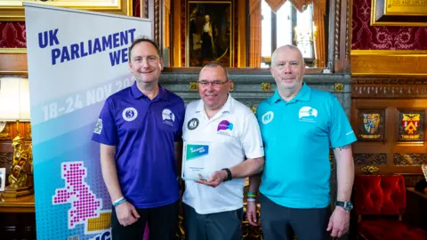 3 Dads Walking posing with award