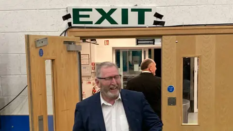 Doug Beattie under a sign saying exit