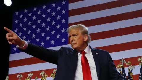 Reuters Donald Trump points to the assemblage  during his rally, with the backdrop of the US flag