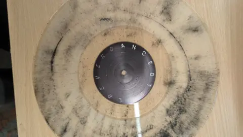 The transparent vinyl with black coal dust particles embedded in it.