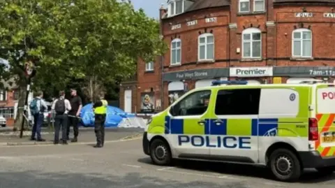 A police van is parked up in Walsall with officers talking to people in the street near a police cordon