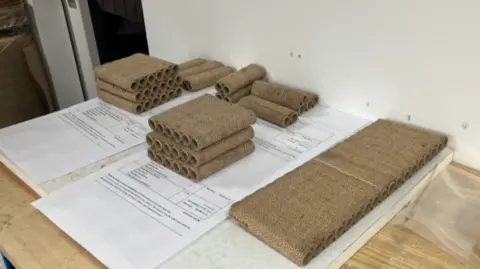 Hessian covered lines of cardboard rolls, in small piles on top of paperwork