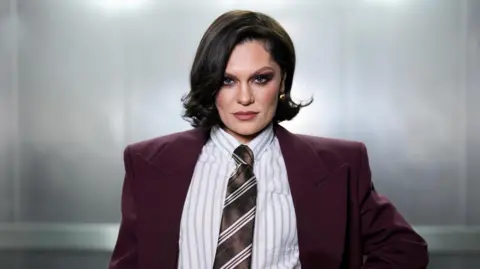 Jessie J looking straight at the camera while wearing a suit and tie