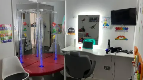 Vikki Irwin/BBC A sensory room featuring chairs, an Ipad, a mirror and toys.
