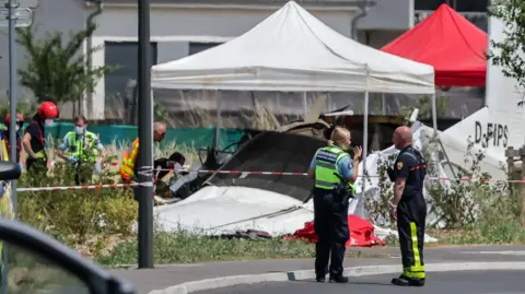 Emergency service workers speak to each other as the attend a light aircraft crash site