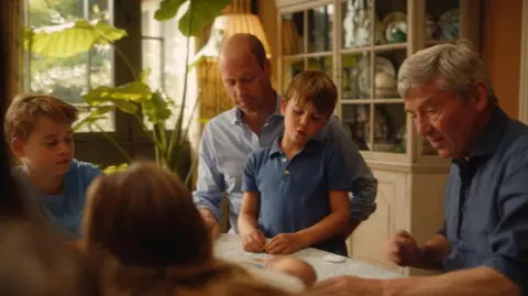 Will Warr/Kensington Palace William, Prince Louis, Prince George, their maternal grandfather Michael Middleton are seen playing a card game at a table 