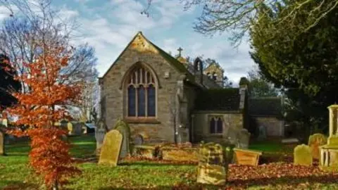 St Mary's Church Front view of St Mary's Church. It has an arched window at the front with headstones and trees in the foreground.