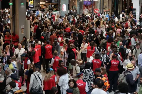 AFP Employees of SNCF railway company speak to passengers waiting for their trains' departure at the Gare Montparnasse train station in Paris on July 26, 2024 as France's high-speed rail network was hit by malicious acts disrupting the transport system hours before the opening ceremony of the Paris 2024 Olympic Games