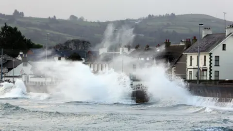 PA Media High winds and sea hitting against the sea wall on the Antrim coast road in Co Antrim