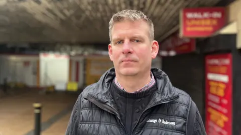 David Walker, stood in front of the closed street, looking at the camera