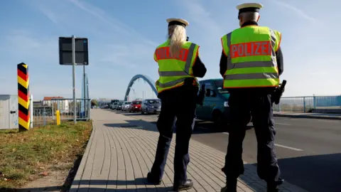 Reuters Two German federal police officers patrol a line of cars along the German-Polish border area in order to detain migrants from Belarus in 2021