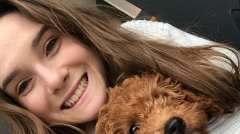 Woman smiling at camera while hugging dog