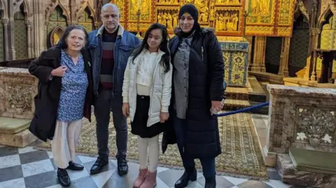 Family handout Pictured is Bushra, Margaret, Rinaad and Khaled. Margaret is wearing a blue top, cream trousers and a long coat while standing next to Khaled who is wearing a denim jacket with a fabric collar, grey jeans and black shoes. Rinaar is wearing white jacket underneath an open white body warmer, black skirt with white tights and pink boots. Bushra wears a black head scarf, black long jacket with a black and white stripe shirt.