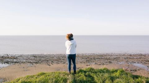 A woman looks out to sea on a Kent beach