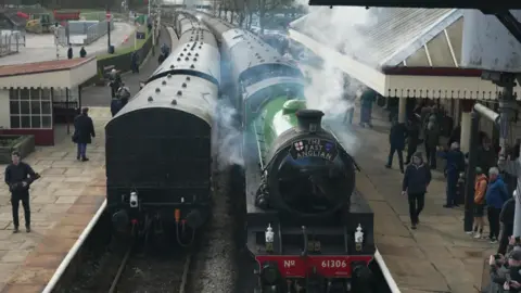 BBC Two steam locomotives waiting at Bury Bolton Street railway station as part of the Legends of Steam event with a number of rail enthusiasts looking at them some taking photos on their mobile phones. 