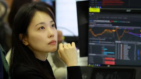 A currency dealer with a thoughtful look as she analyses charts displayed on monitorsin a foreign exchange dealing room at the Hana Bank headquarters in Seoul