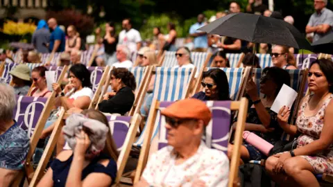 PA People sit on deck chairs in Victoria Embankment Gardens, London.