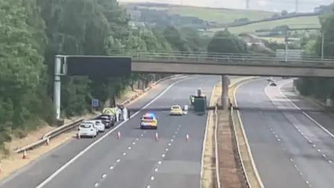 A drone shot of the section of empty motorway, with police vehicles to the left