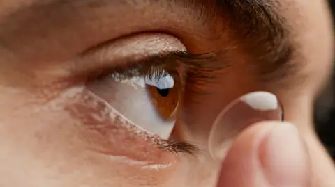 Getty Images A close-up image of a woman putting a contact lens into her eye