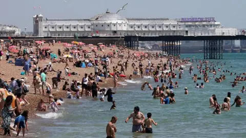 Getty Images People on the beach and in the sea at Brighton. Brighton Pier is in the background. 