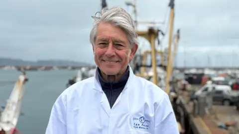 Brixham fish merchant Ian Perkes wearing a shite coast and smiling at the camera