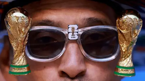 Getty Images A close-up shot of a man wearing sunglasses with a World Cup miniature on each side.