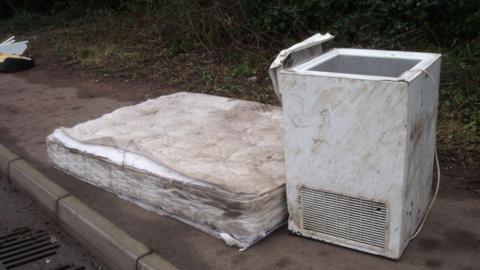 A mattress and a fridge-freezer left on a street