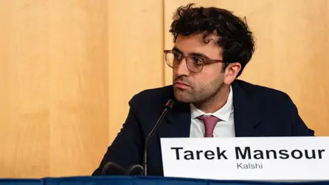 Bloomberg via Getty Images Tarek Mansour, co-founder of Kalshi, sits behind a mcirophone in a dark suit, with a white shirt and red tie during a joint SEC-CFTC roundtable at SEC headquarters in Washington, DC, US, on Monday, Sept. 29, 2025.