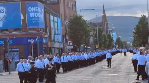 Pacemaker Men marching on road in white shirts and black ties 