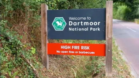 A sign that says Welcome to Dartmoor National Park - High Fire Risk - no open fires or barbecues.