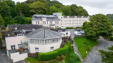 Exterior view of Stradey Park Hotel, a large cream coloured four-storey building with parked cars outside.
