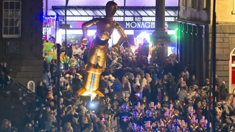 Stuart Walker A parade featuring lights, projections, and a large inflatable C3PO from Star Wars