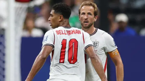 Reuters Harry Kane and Jude Bellingham standing next to each other while on the pitch playing for England. 