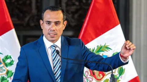 Getty Images Peru's interim president José Jerí stands at a podium wearing a blue suit, white shirt, and blue striped tie.