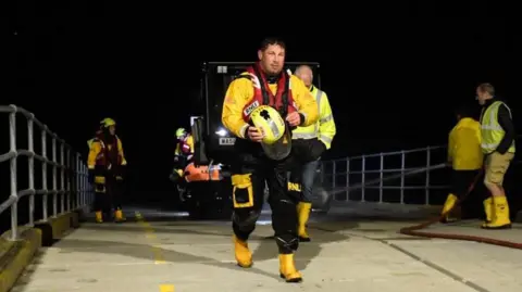 Wells RNLI Volunteers making their way back up the lifeboat ramp, with the boat behind on a vehicle.