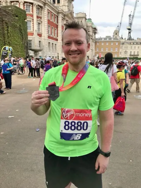 Peter Rossiter lasting  connected  the thoroughfare  aft  moving  a race, wearing a lime greenish  sports apical  and achromatic  shorts. He is holding up   the medal which is connected  a lanyard astir   his neck.