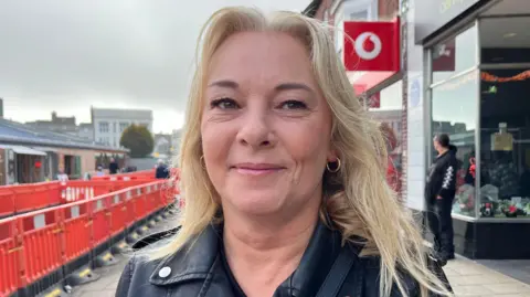 Andrew Turner/BBC Rachel Hillier in Great Yarmouth town centre. She has blonde hair and is wearing a black leather jacket.