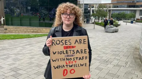 A woman holding a cardboard sign