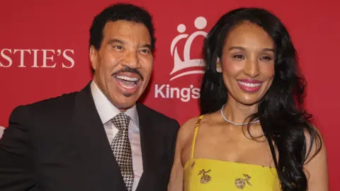 EPA/Shutterstock Lionel Richie and his partner Lisa Parigi standing in front of a King's Trust backdrop, both smiling