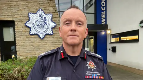 BBC Mark Preece wearing his uniform outside a Gloucestershire Fire and Rescue Service station