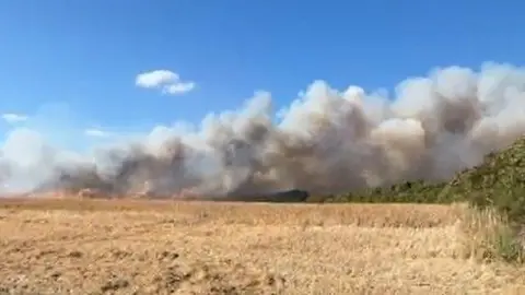 Kevin Massiah Smoke billows into the sky from a fire on a farmer's field. 