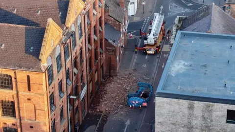Aerial view of the collapse of a former factory building in Wharf Street South in Leicester city centre with fire engines in attendance.