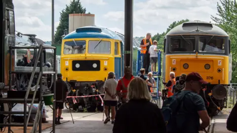 GWSR A railway works shed with two locomotives and people milling around