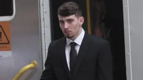 Kian Bateman dressed in a dark suit arriving in court for his murder trial