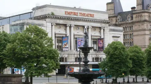 Geograph/Ian Greig Front exterior of two-tier Empire Theatre, which has white stone pillars and front with trees and fountain on St George's plaza opposite